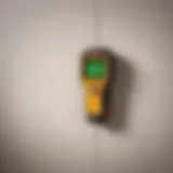 A close-up of a stud finder tool in action against a wall.